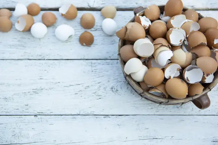 10 February 2023: Easter, broken eggs shells on light wood in a basket