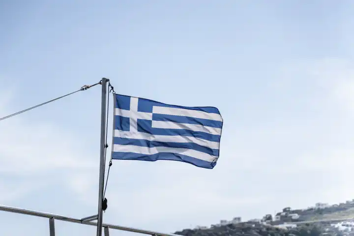 Mykonos, Greece - 10 May 2023: Greek flag on a boat against blue sky on Mykonos in Greece