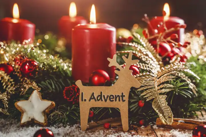 Adventskranz mit brennenden Kerzen zu Weihnachten mit einem Schild in Rentier Form mit Text: 1. Advent (Erster Advent). Adventszeit Konzept FOTOMONTAGE 