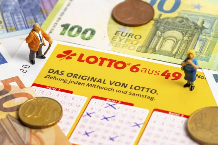 Miniaturfiguren stehen auf einem Lotto 6 aus 49 Spielschein mit Euro Bargeld Scheinen und Münzen. Glücksspiel Lotterie 
