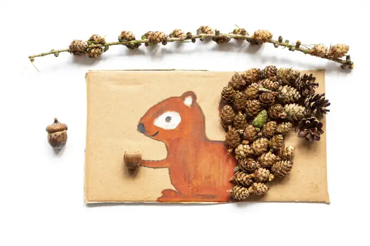 Kinderspaß mit Herbstlaub: Kreatives Basteln zu Hause. Eine Kollage von einem Eichhörnchen mit Wasserfarbe ausgemalt und mit Tannenzapfen verziert 