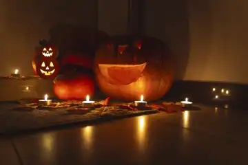 Augsburg, Bavaria, Germany - 18 October 2023: Halloween decoration in front of an apartment door in the dark. Burning candles glow around spooky decorated Halloween pumpkins in front of a door
