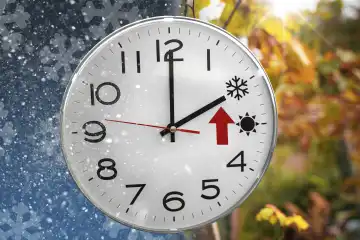 Uhr mit zwei Jahreszeiten und einem roten Pfeil für die Zeitumstellung im Herbst auf Winterzeit. Schnee und Sonnenschein FOTOMONTAGE