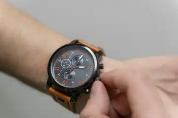 Ein Mann stellt die Uhrzeit an seiner Armbanduhr ein. Zeitumstellung Konzept