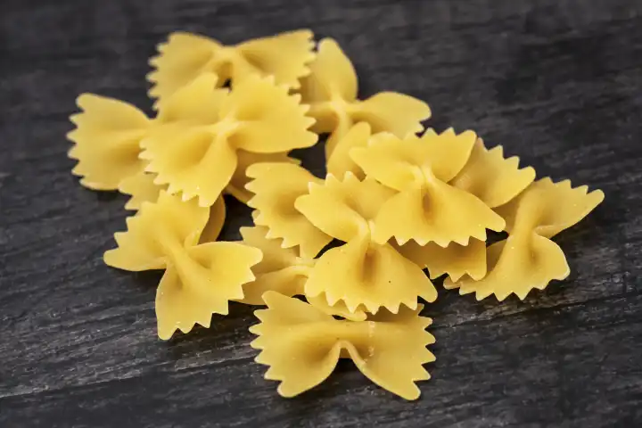Farfalle pasta noodles on a black wooden background