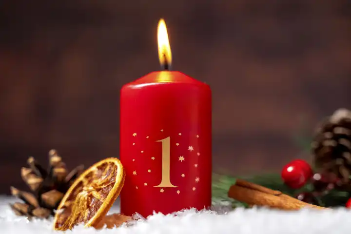 1. Adventskerze brennt, Kerze zum ersten Advent mit Weihnachtsdekoration