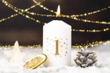 Erster Advent weiße Kerze brennt am 1. Adventssonntag in Schnee  und Winter Dekoration
