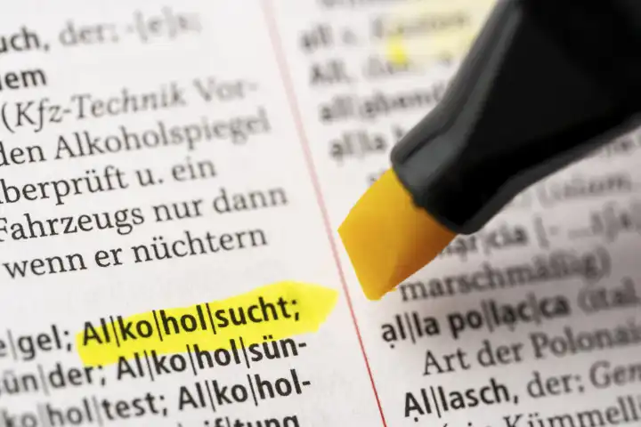 Das Wort Alkoholsucht in einem Wörterbuch Duden markiert mit einem Stift