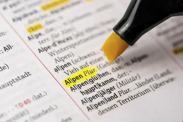 Das Wort Alpen in einem Wörterbuch Duden markiert mit einem Stift