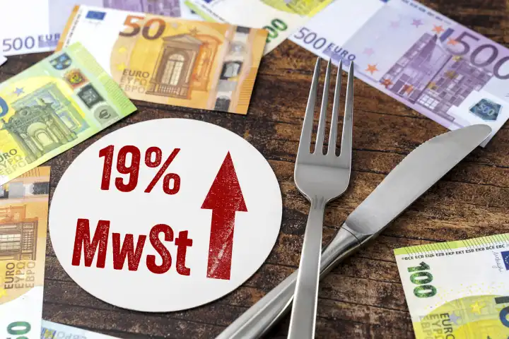 Messer und Gabel zusammen mit Euro Geldscheinen neben einem Bierdeckel mit der Aufschrift 19 % MwSt. Mehrwersteuererhöhung in der Gastronomie ab 2024 FOTOMONTAGE