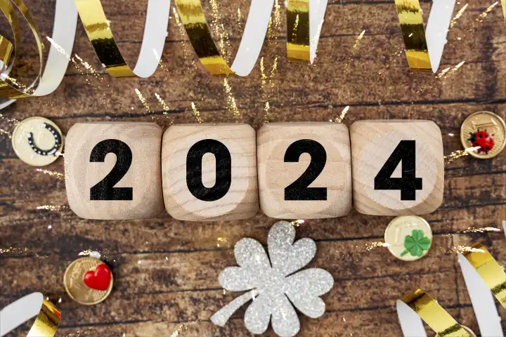  Frohes Neues Jahr 2024, Symbolbild Jahreswechsel an Silvester. Holz Würfel mit der Aufschrift 2 0 2 4 umgeben von Glücksbringern FOTOMONTAGE