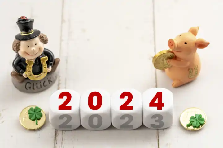 Jahreswechsel von 2023 auf 2024, Würfel mit Aufschrift 2024 neben Glücksschwein und Schornsteinfeger. Silvester und Neujahr Konzept FOTOMONTAGE