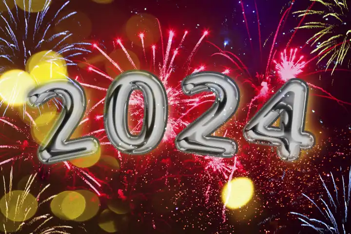Neujahrsgruß und Silvester Konzept, Jahreszahl 2024 geschrieben mit silbernen Ballons vor schrillem bunten Feuerwerk am Himmel FOTOMONTAGE