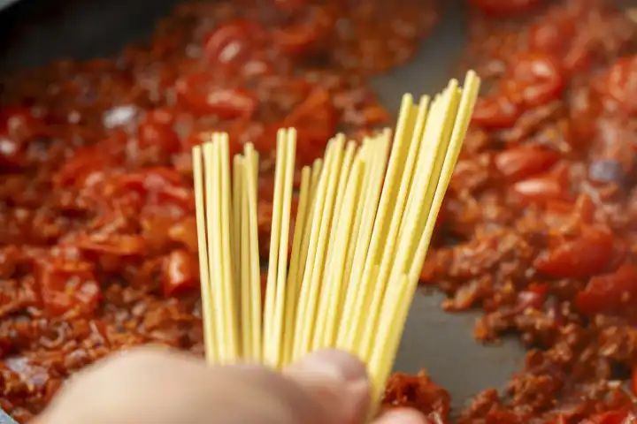 Spaghetti Nudeln vor einer Tomaten Bolognese Soße in einer Pfanne