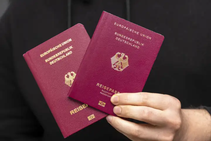 Mann hält Reisepässe der Bundesrepublik Deutschland in der Hand. Deutscher Reisepass