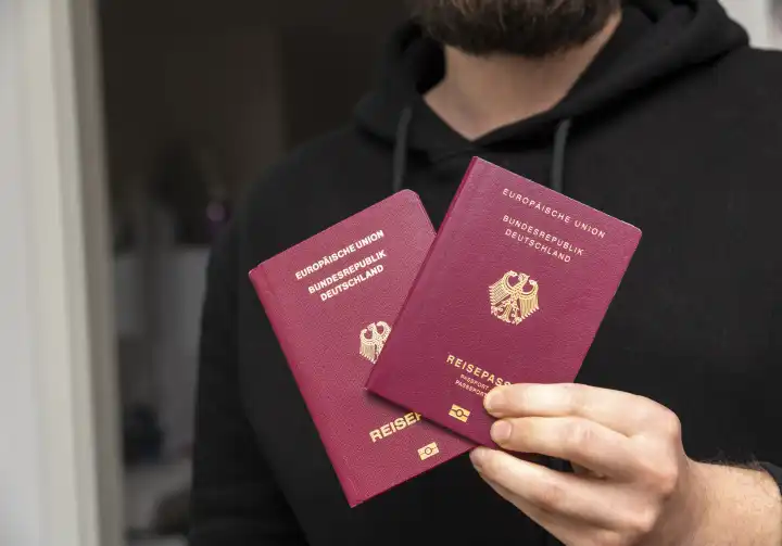 Mann hält Reisepässe der Bundesrepublik Deutschland in der Hand. Deutscher Reisepass
