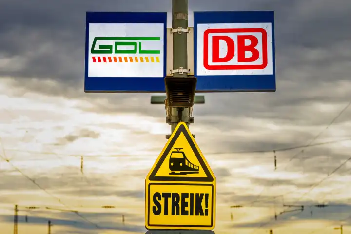 GDL (Gewerkschaft Deutscher Lokomotivführer) und DB (Deutsche Bahn) Logo auf einer Tafel an einem Bahnhof mit einem Warnschild mit der Aufschrift Streik! FOTOMONTAGE