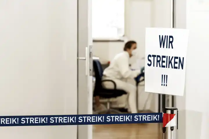 Wir Streiken! Schild vor einem Behandlungszimmer einer Arztpraxis. Symbolbild Streik von Ärzten und Medizinischen Fachangestellten. FOTOMONTAGE 