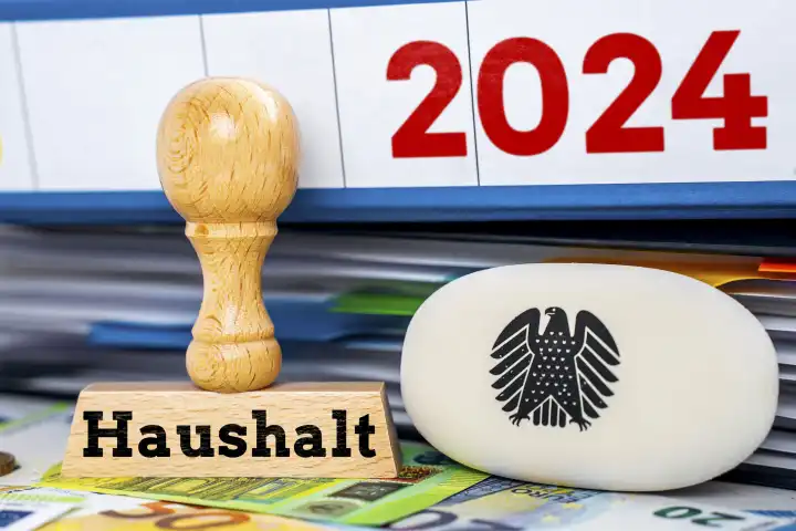 Bundeshaushalt 2024, Ein Stempel neben Ordnern und Euro Geldscheinen mit einem Logo des deutschen Bundesadlers mit der Aufschrift: Haushalt FOTOMONTAGE