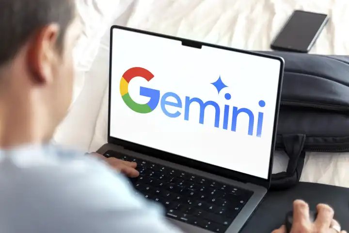 Mann an Laptop Computer mit dem KI-Chatbot Google Gemini Logo auf dem Bildschirm. FOTOMONTAGE