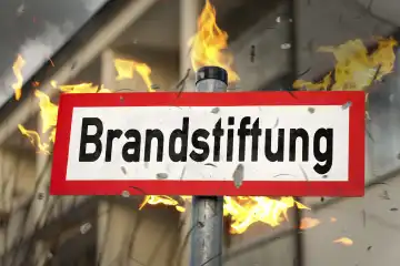 Brandstiftung Schrift auf einem Schild vor einem brennenden Wohnhaus. FOTOMONTAGE