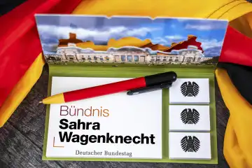 BSW, Bündnis Sahra Wagenknecht Partei Logo auf einem Notizblock mit Bundesadler und Deutschem Bundestag abgebildet neben einer Deutschland Fahne. FOTOMONTAGE
