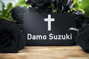 Can Musiker Damo Suzuki ist am 9 Februar im Alter von 74 gestorben Symbolbild. Schwarze Rosen mit einem Schild und einem Kreuz mit der Aufschrift Damo Suzuki. FOTOMONTAGE