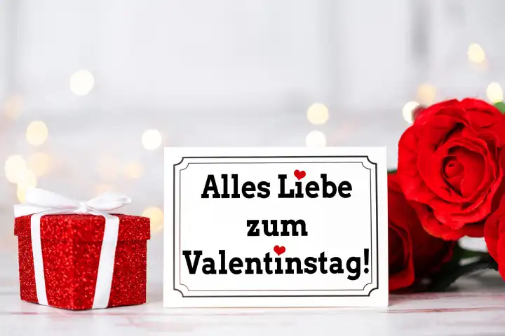 Alles Liebe zum Valentinstag, Gruß auf einer Grußkarte neben einem roten Geschenk und einer roten Rose. FOTOMONTAGE