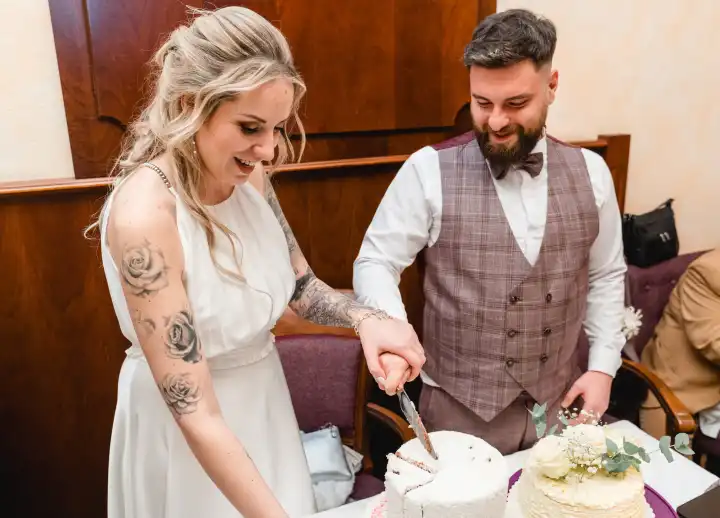 Augsburg, Bavaria, Germany - January 19, 2024: Bride and groom cut the wedding cake together