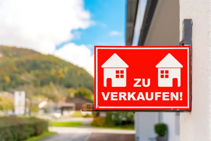Wohnung, Haus oder Immobilie zu verkaufen! Schriftzug auf einem roten Schild an einer Hauswand. FOTOMONTAGE