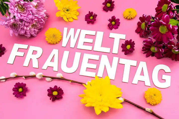 Weltfrauentag, Schriftzug auf rosa Hintergrund mit bunten Blumen und Blüten. Symbolbild Gruß zum Internationalen Frauentag am 8 März