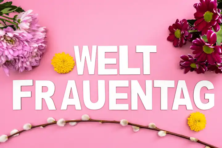 Weltfrauentag, Schriftzug auf rosa Hintergrund mit bunten Blumen und Blüten. Symbolbild Gruß zum Internationalen Frauentag am 8 März