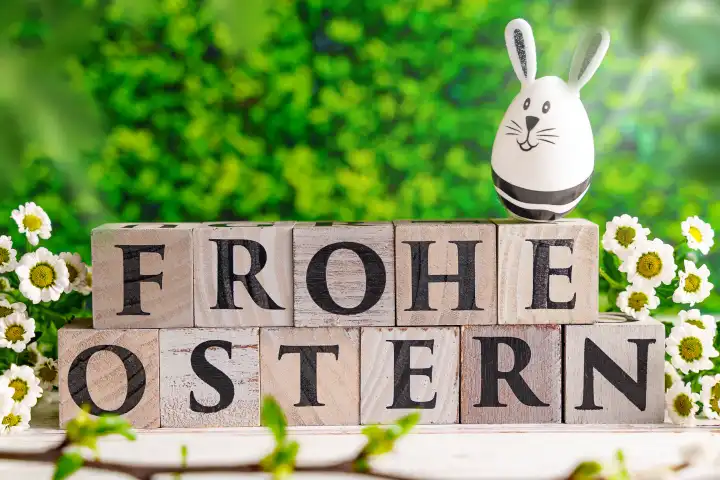 Frohe Ostern! geschrieben mit Holzwürfeln, Osterhasen Ei und frühlings Blumen. Ostern Symbolbild