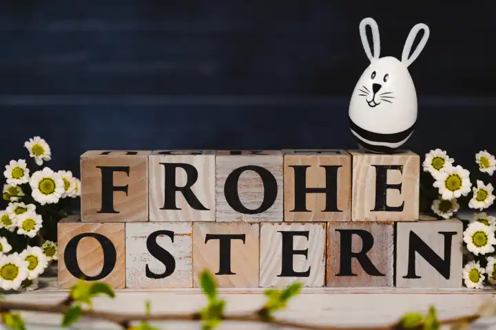 Frohe Ostern! geschrieben mit Holzwürfeln, Osterhasen Ei und frühlings Blumen. Ostern Symbolbild