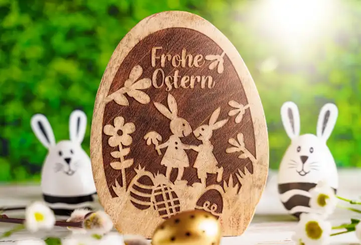 Frohe Ostern! Gruß auf einem Osterei aus Holz neben Osterdekoration