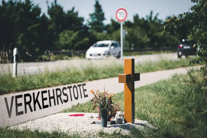 Bundesstraße daneben ein Kreuz und Text: Verkehrstote. Symbolbild für Zahlen der Toten Menschen im Verkehr. FOTOMONTAGE