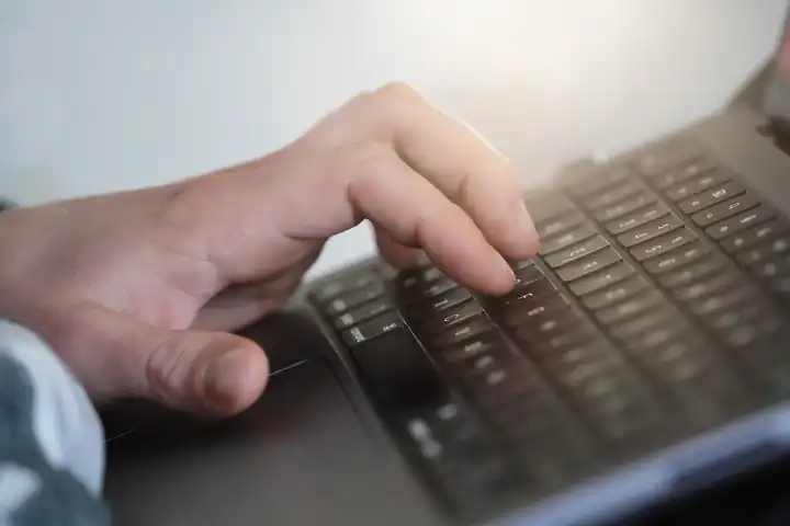 Mann bedient mit der Hand eine Computer Tastatur. Arbeiten Zuhause am Laptop