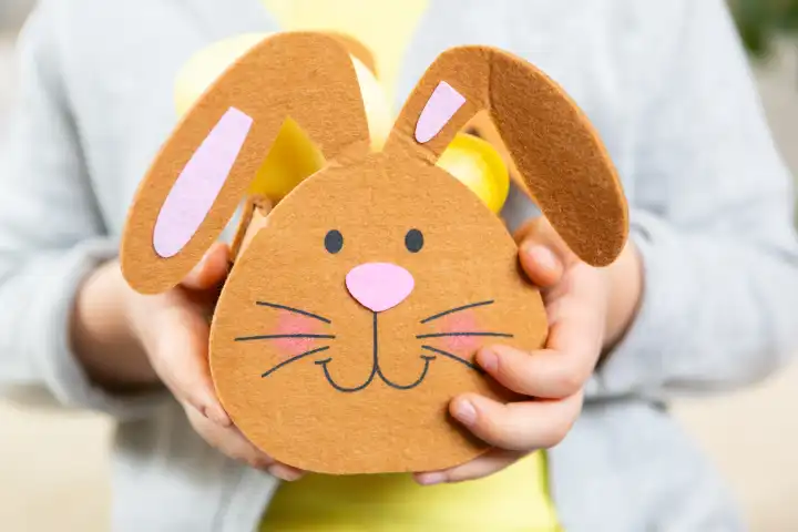 3 March 2024: Little boy holding a felt Easter nest in the shape of a bunny filled with Easter eggs at Easter