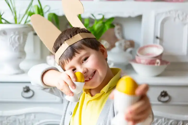 Kleiner Junge spielt mit gelben gefärbten Ostereiern. Glückliches Kind an Ostern