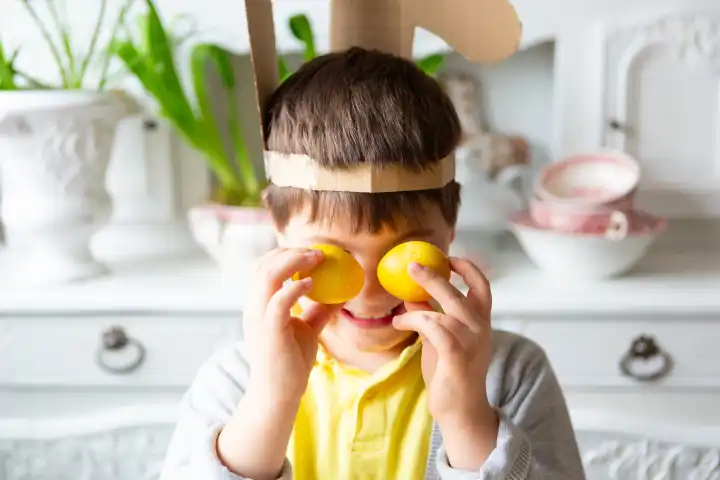 Kleiner Junge spielt mit gelben gefärbten Ostereiern. Glückliches Kind an Ostern