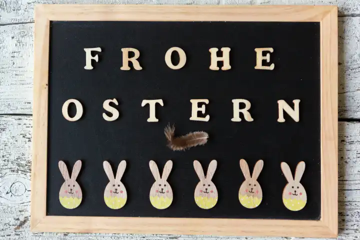 3 March 2024: Happy Easter, greeting made of wooden letters on a chalkboard with cheerful Easter bunnies
