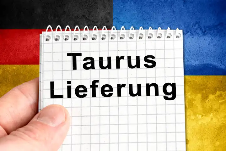 Hand hält einen Notizblock vor Deutschland und Ukraine Landesflaggen mit Aufschrift: Taurus Lieferung. FOTOMONTAGE