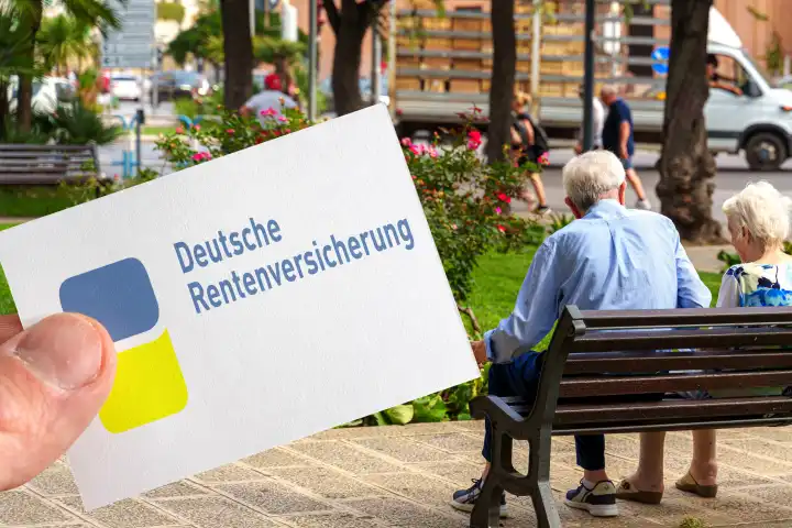 Germany - March 11, 2024: German pension insurance logo on a sign held by a hand in front of an old pensioner couple. PHOTOMONTAGE