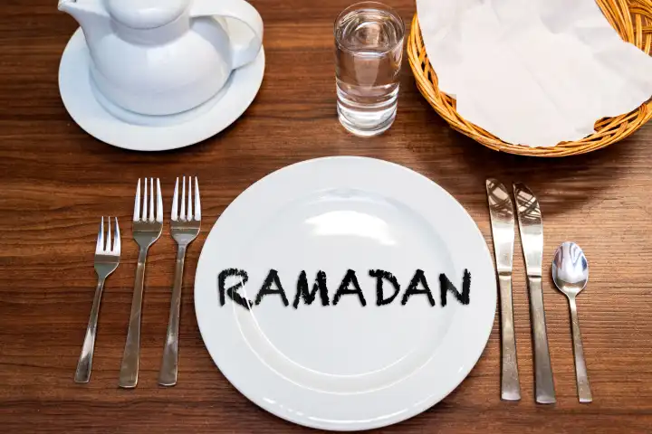 11 March 2024: Ramadan, lettering on an empty plate at a laid table. PHOTOMONTAGE