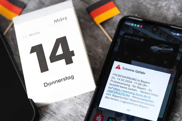 Langweid, Bavaria, Germany - March 14, 2024: Theme picture test alarm on March 14 at 11 a.m. in Bavaria. Smartphone with the warning message: Extreme danger, on the screen