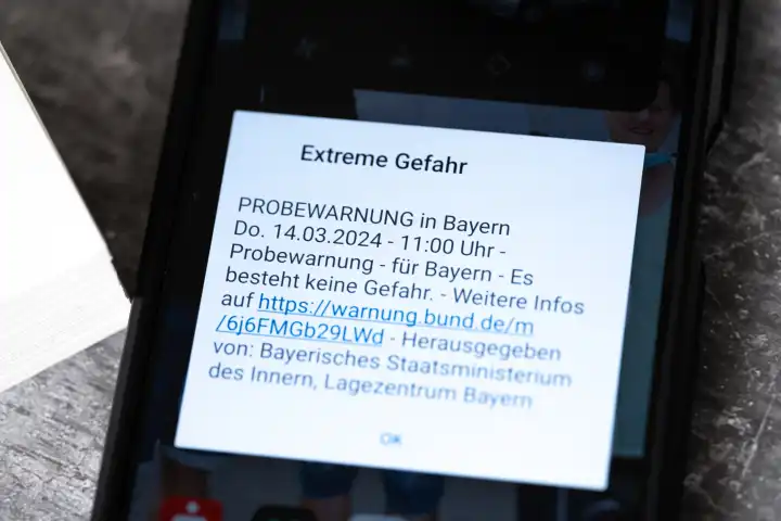 Langweid, Bavaria, Germany - March 14, 2024: Theme picture test alarm on March 14 at 11 a.m. in Bavaria. Smartphone with the warning message: Extreme danger, on the screen