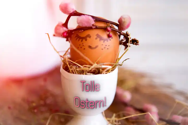 14 March 2024: Great Easter! Greeting on an egg cup with a painted Easter egg with face and crown. PHOTOMONTAGE