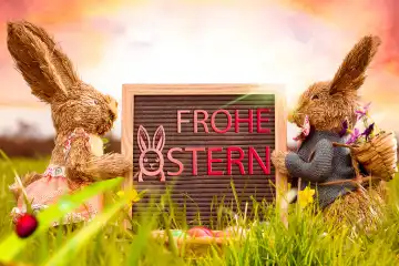 15 March 2024: Happy Easter, lettering on a plaque next to two Easter bunnies. PHOTOMONTAGE