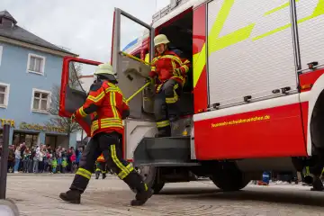 Schwabmünchen, Bavaria, Germany - March 17, 2024: Firefighters practice an operation with firefighter uniform or clothing, they are in a hurry and get out of the fire truck. Exercise deployment of the Schwabmünchen fire department at a street festival