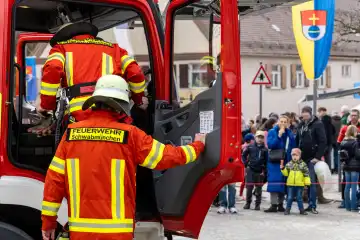 Schwabmünchen, Bavaria, Germany - March 17, 2024: Firefighters practice an operation with firefighter uniform or clothing, they are in a hurry and get out of the fire truck. Exercise deployment of the Schwabmünchen fire department at a street festival